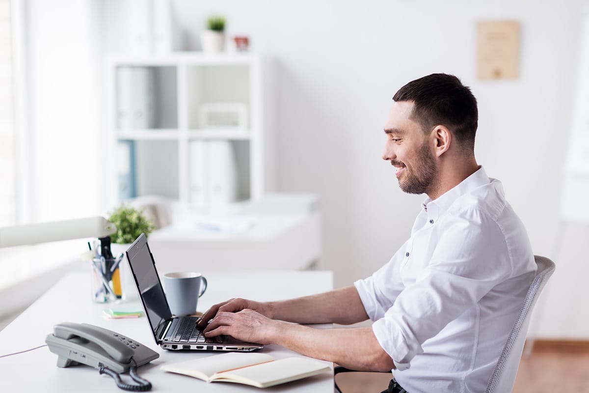 happy businessman with laptop at office P8J4GRH